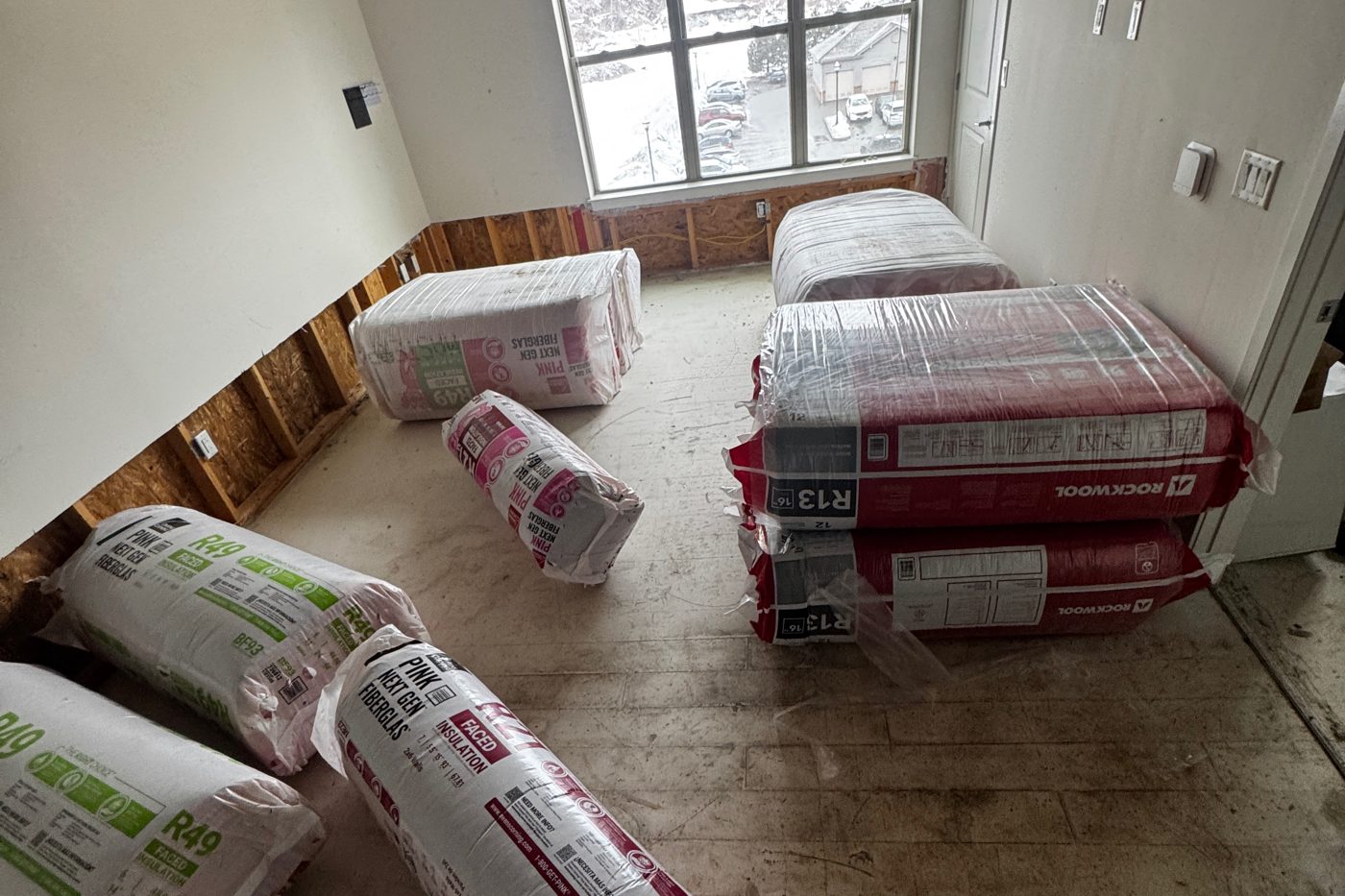 Bags of fiberglass and mineral wool insulation in a room being renovated, ready to install