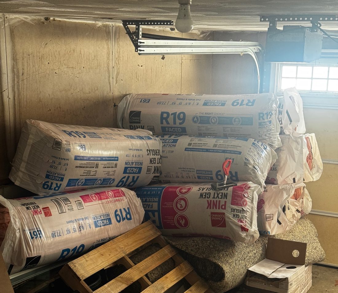 Bundles of R-19 faced fiberglass insulation batts stacked in a garage before installation