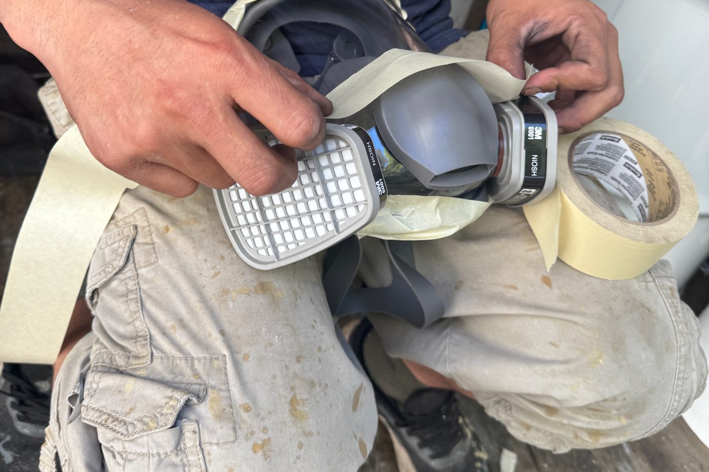 Installer preparing a respirator with fresh cartridges and tape before spraying foam insulation