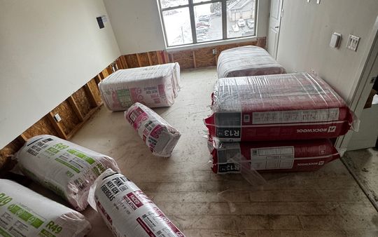 Bags of fiberglass and mineral wool insulation in a room being renovated, ready to install