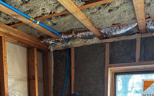 Wall cavities filled with insulation and a foil-faced ceiling during an insulation job near a new window