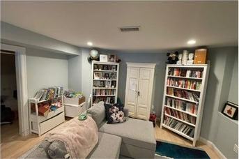 Finished basement living room with built-in shelves and a window