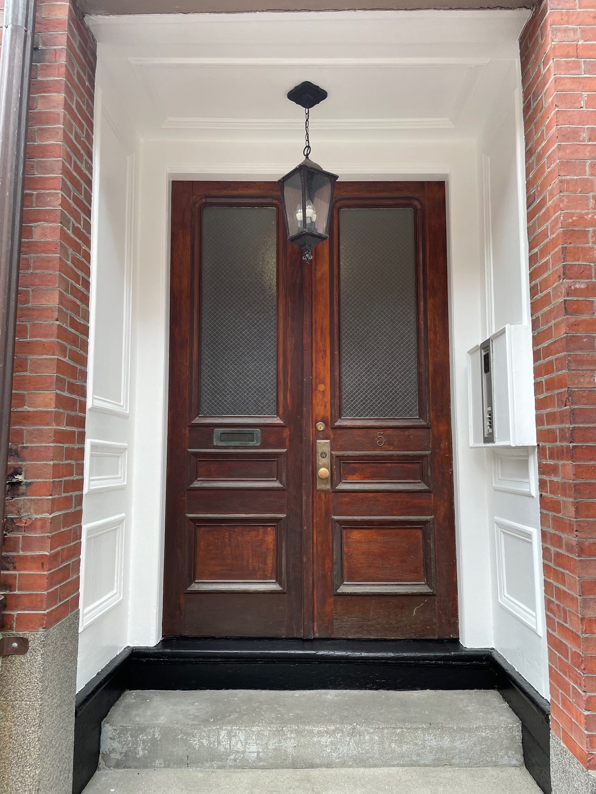 Restored wooden front door in a brick entry