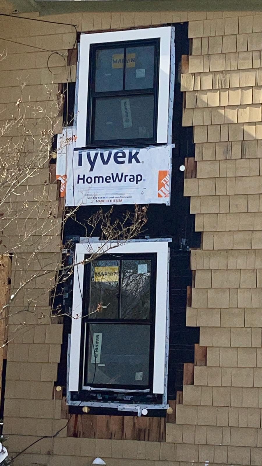 New windows being installed with house wrap during an exterior renovation
