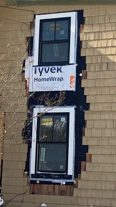 New windows being installed with house wrap during an exterior renovation