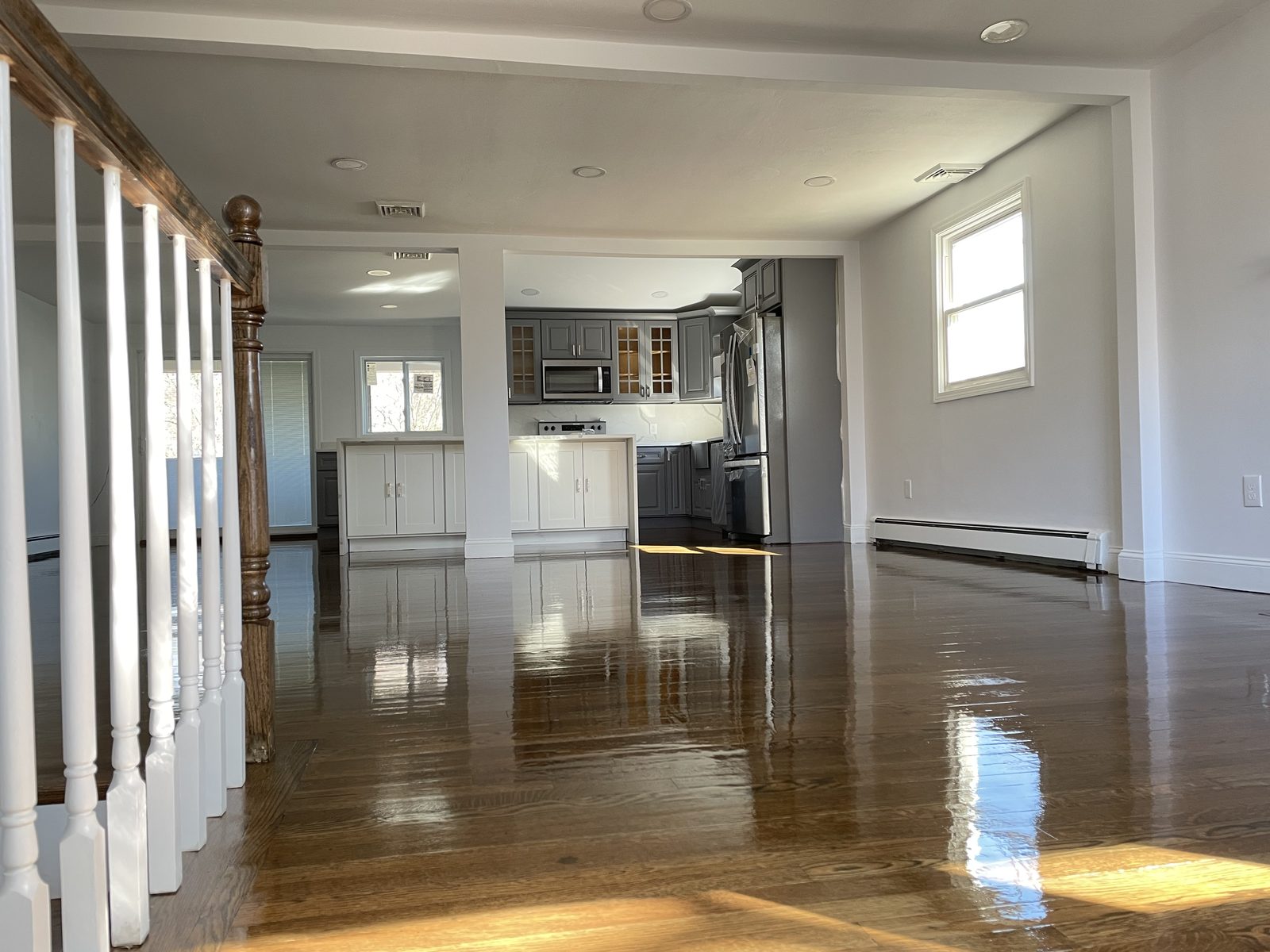 Renovated open living space with new hardwood floors and a white stair rail