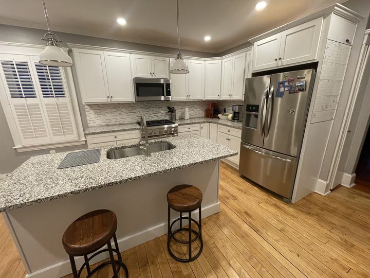 Finished white kitchen remodel with granite island and stainless appliances
