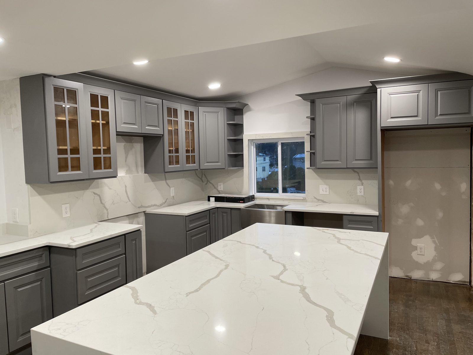 Gray kitchen with quartz island and glass-front cabinets